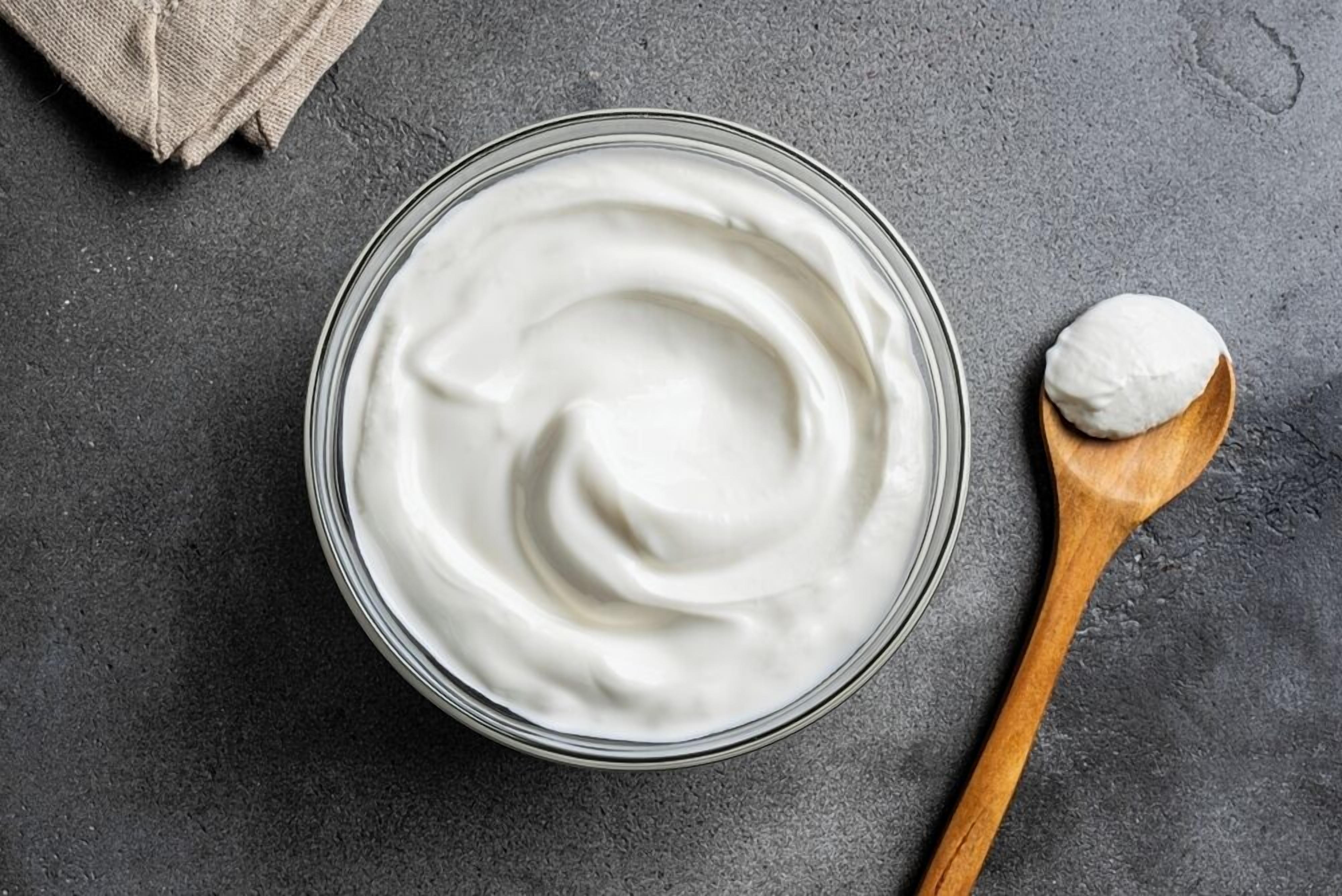 A glass bowl of white substance with a wooden spoon beside it.