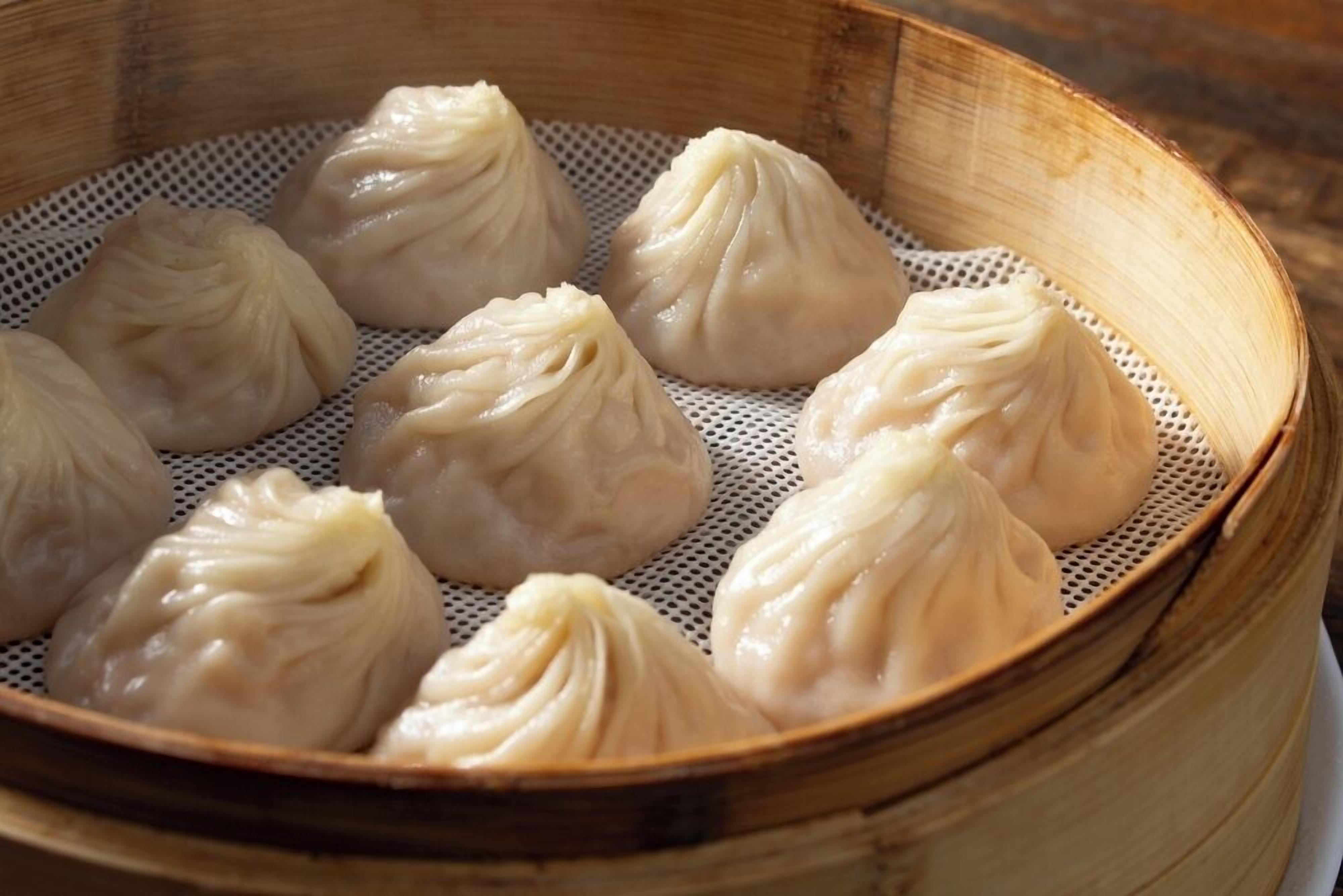 Un panier vapeur en bambou contenant plusieurs raviolis.