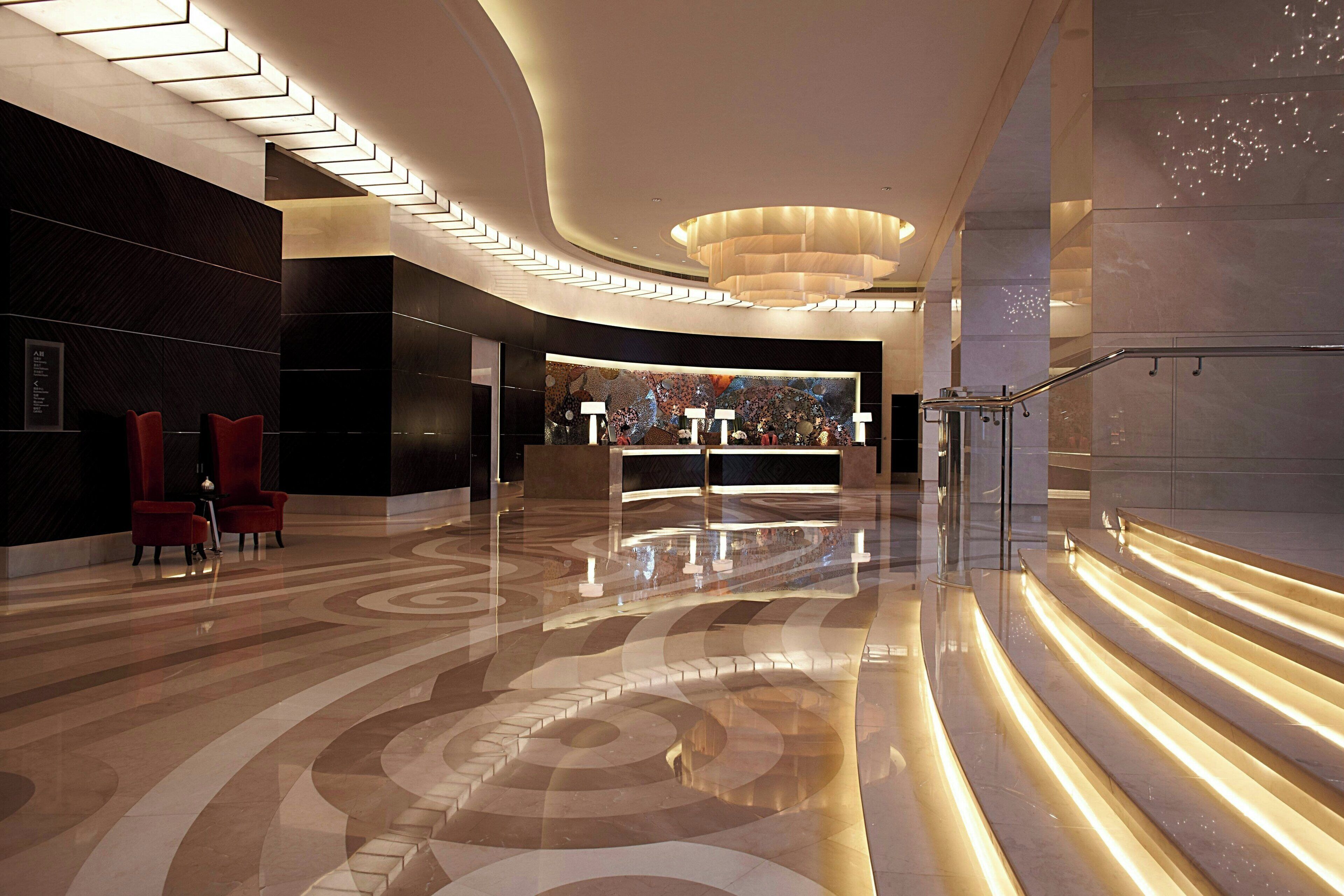 Eine moderne Lobby mit gewölbter Decke, einer Rezeption und einer Treppe.