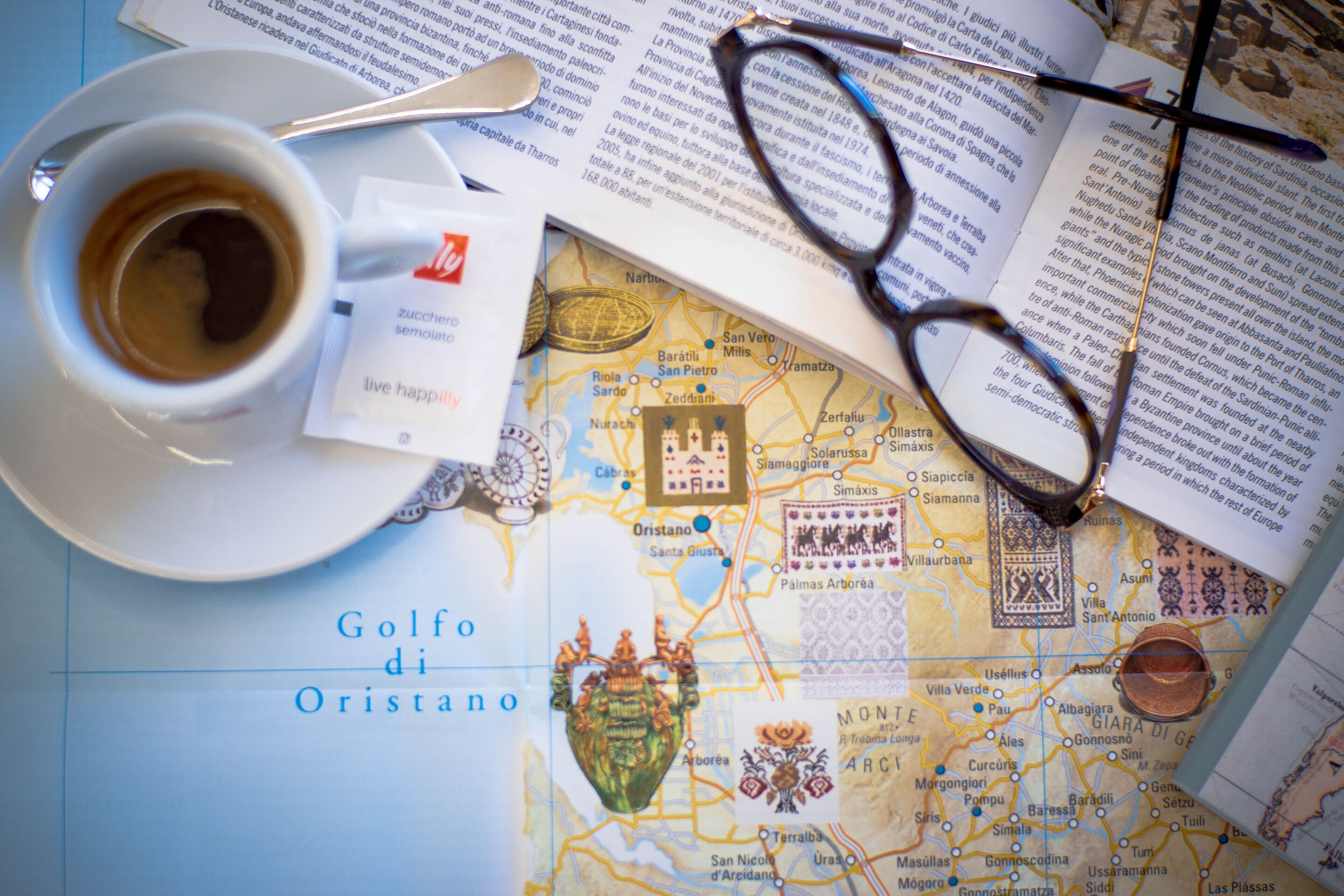 A map with a coffee cup and glasses on top.