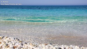 Une plage de galets bordée d’une eau turquoise et cristalline.