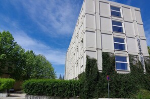 A multi-story building with a modern architectural design, featuring a series of windows and a visible entrance. - Mistral Hotel (Oristano)