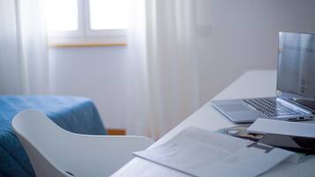Una habitación de hotel con escritorio, ordenador portátil y documentación.