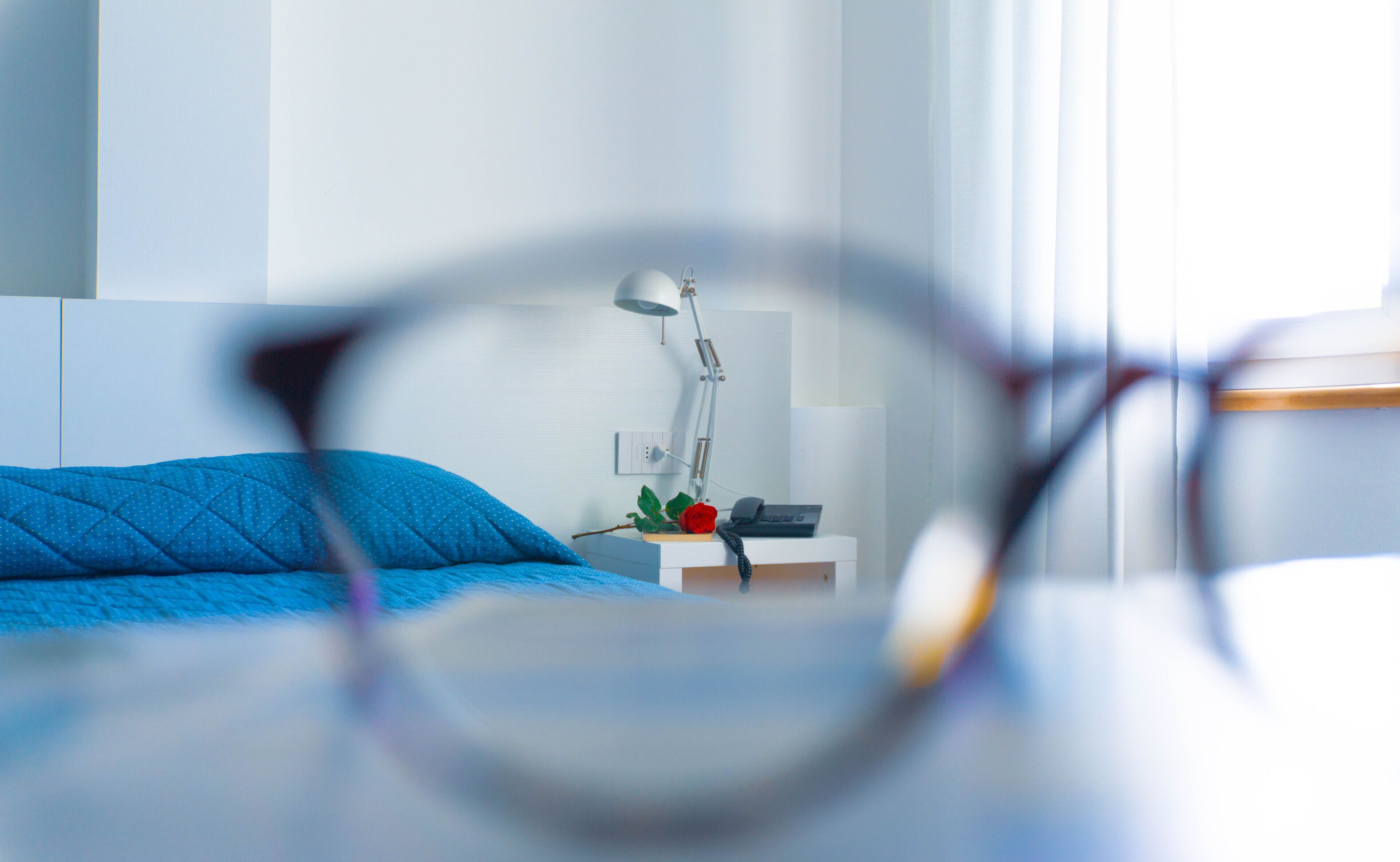 A bedroom with a bed, a bedside table with a lamp, and a telephone.