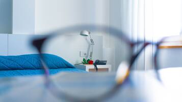 A bedroom with a bed, a bedside table with a lamp, and a telephone.