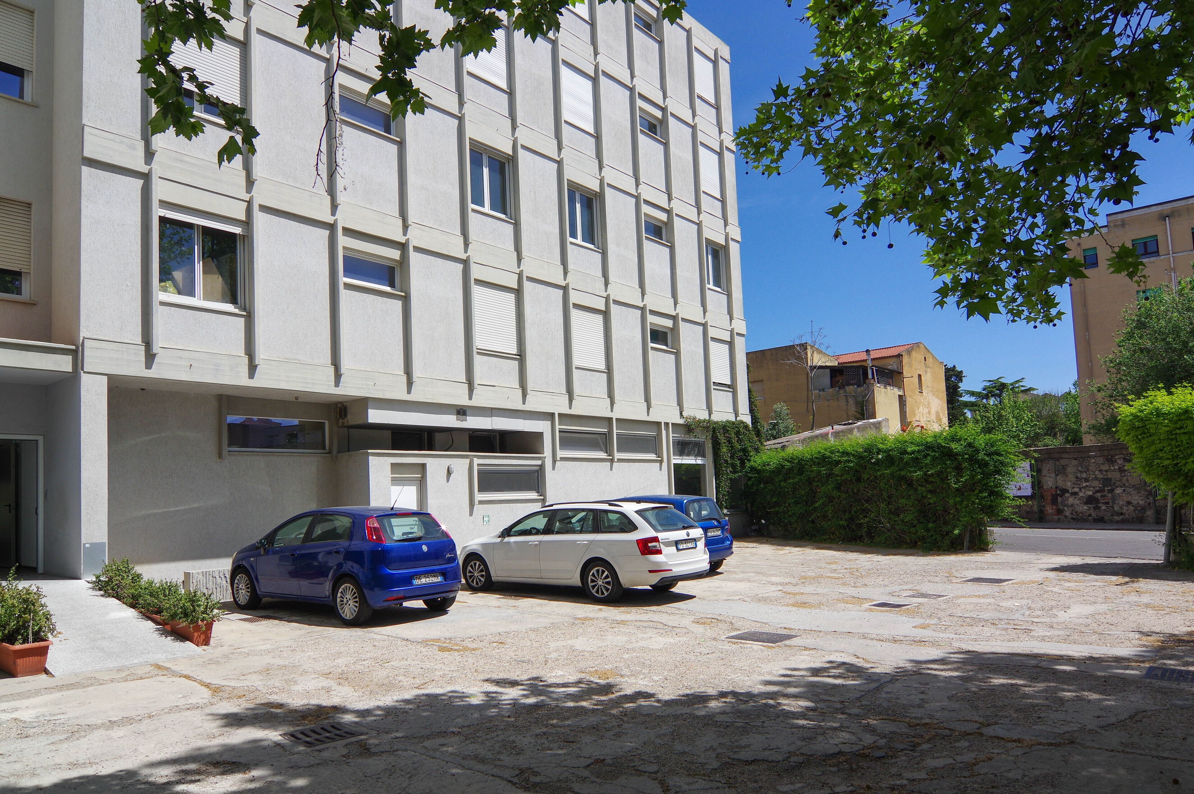 A building with a parking area, two cars parked in front, and a clear sky.