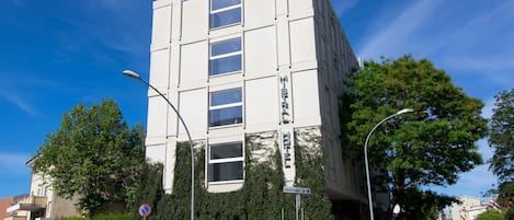 Un hotel moderno con fachada blanca, múltiples ventanas y un letrero que indica que es un hotel.
