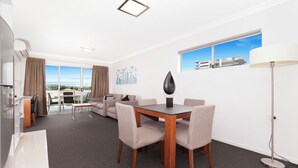 A modern hotel room with a dining area, a sofa, a coffee table, and a view of the city. - Hotel Chino (Woolloongabba)