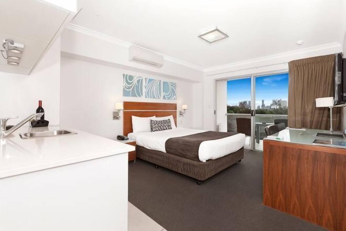 Une chambre dâhĂŽtel avec un lit, un bureau, un lavabo et une vue sur la ville.