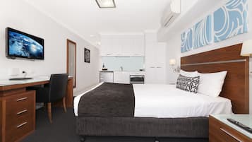 Habitación de hotel con cama, escritorio, silla y kitchenette.