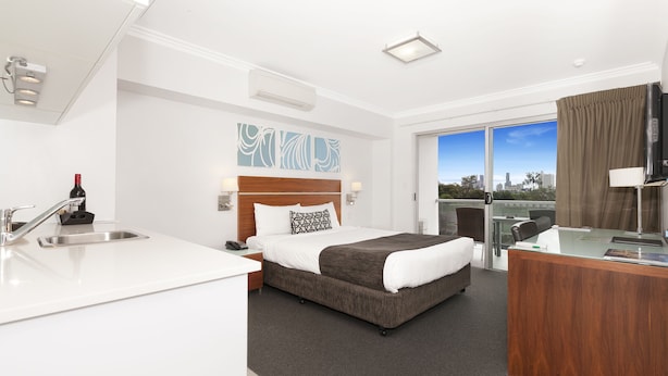 A hotel room with a bed, a desk, a sink, and a city view. - Hotel Chino (Woolloongabba)