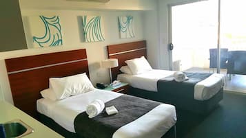 Habitación de hotel con dos camas, minibar y vistas al exterior.