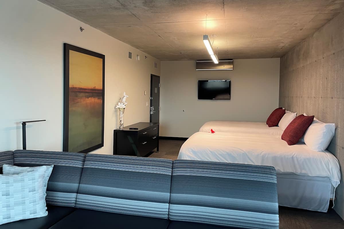 Une chambre d’hôtel avec un grand lit, un canapé, un bureau, une télévision et un tableau au mur.