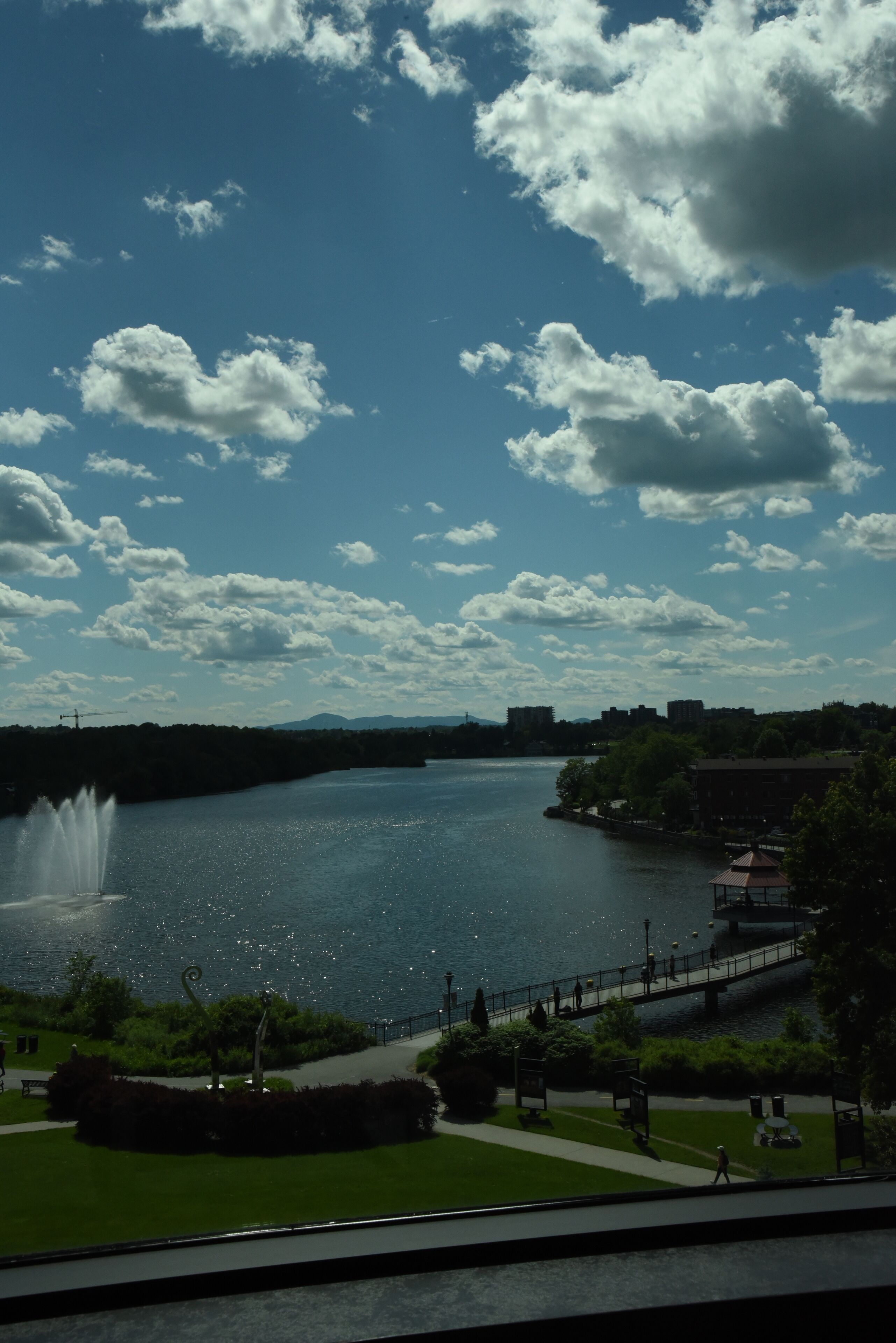 A river with a fountain, a bridge, and a park with a gazebo.