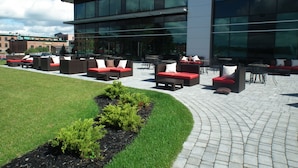 An outdoor seating area with multiple sofas and chairs, a well-maintained lawn, and a modern building with large windows in the background.