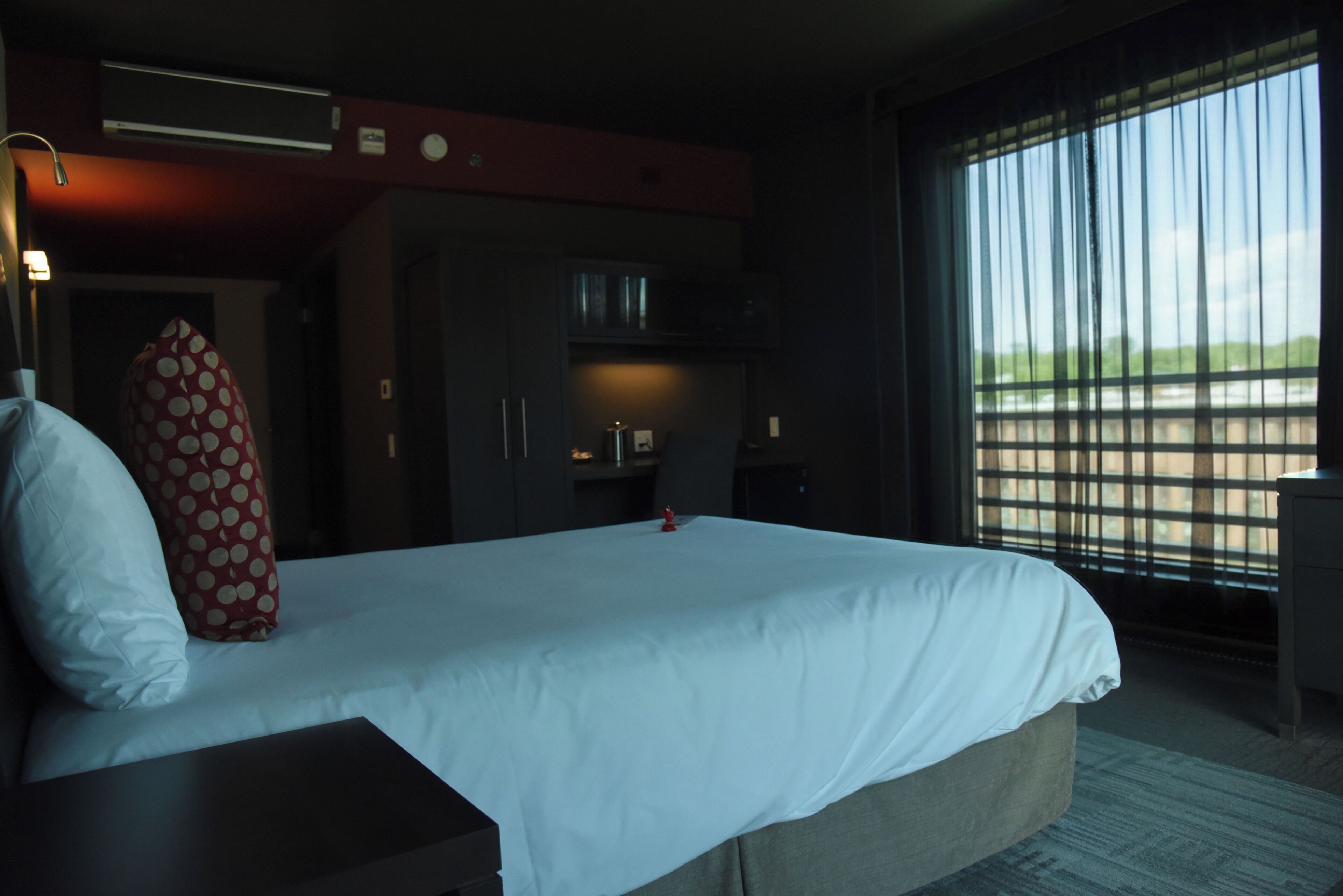 Ein Hotelzimmer mit einem großen Bett, einem Schreibtisch, einem Kleiderschrank und einem Fenster mit Blick.