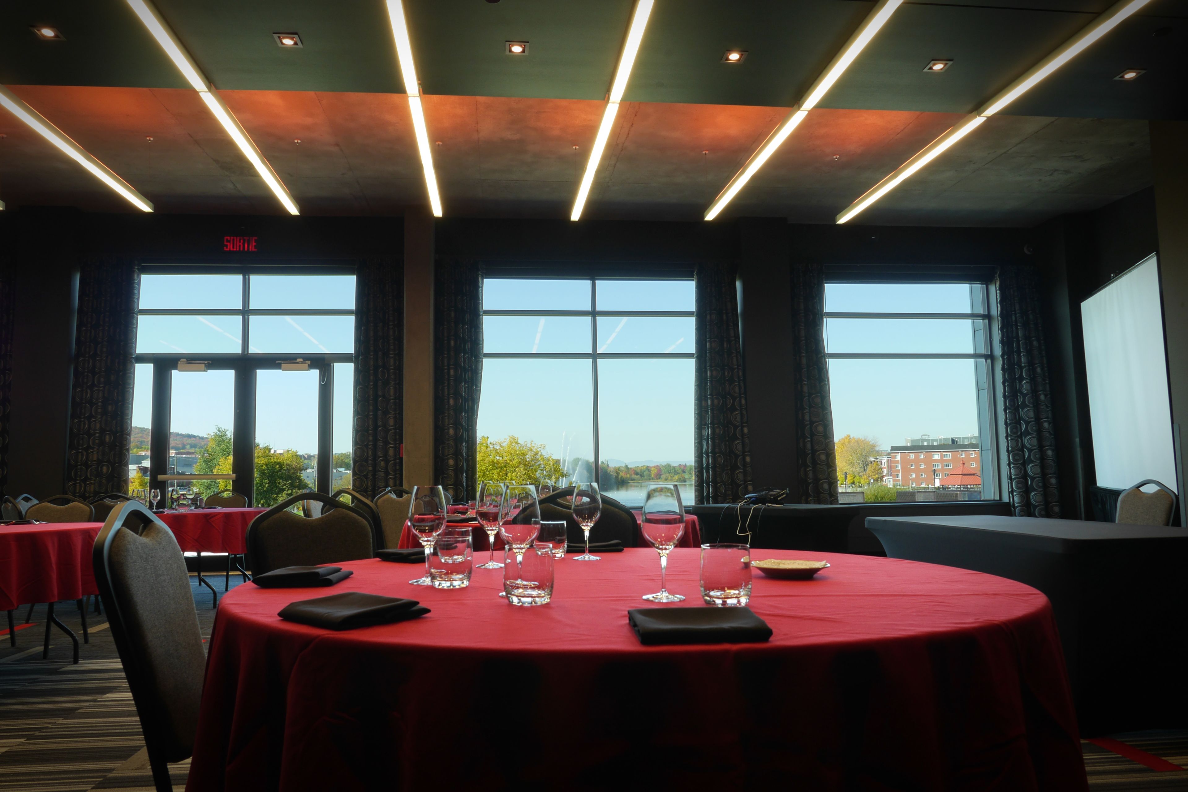 Una sala conferenze con un tavolo rosso, sedie e bicchieri da vino.