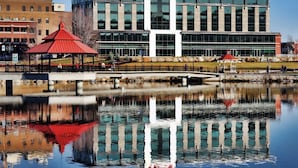 A modern building with a Times sign, a reflection in a water body, and a red-roofed pavilion.