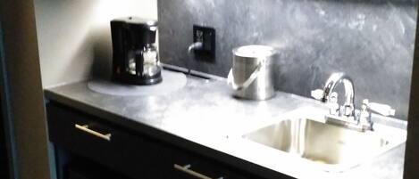 Een kleine keuken met een magnetron, koffiezetapparaat en spoelbak.