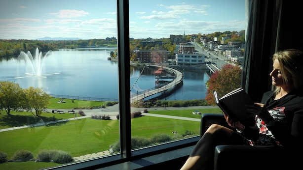 A room with a large window offering a view of a lake, a fountain, and a bridge.