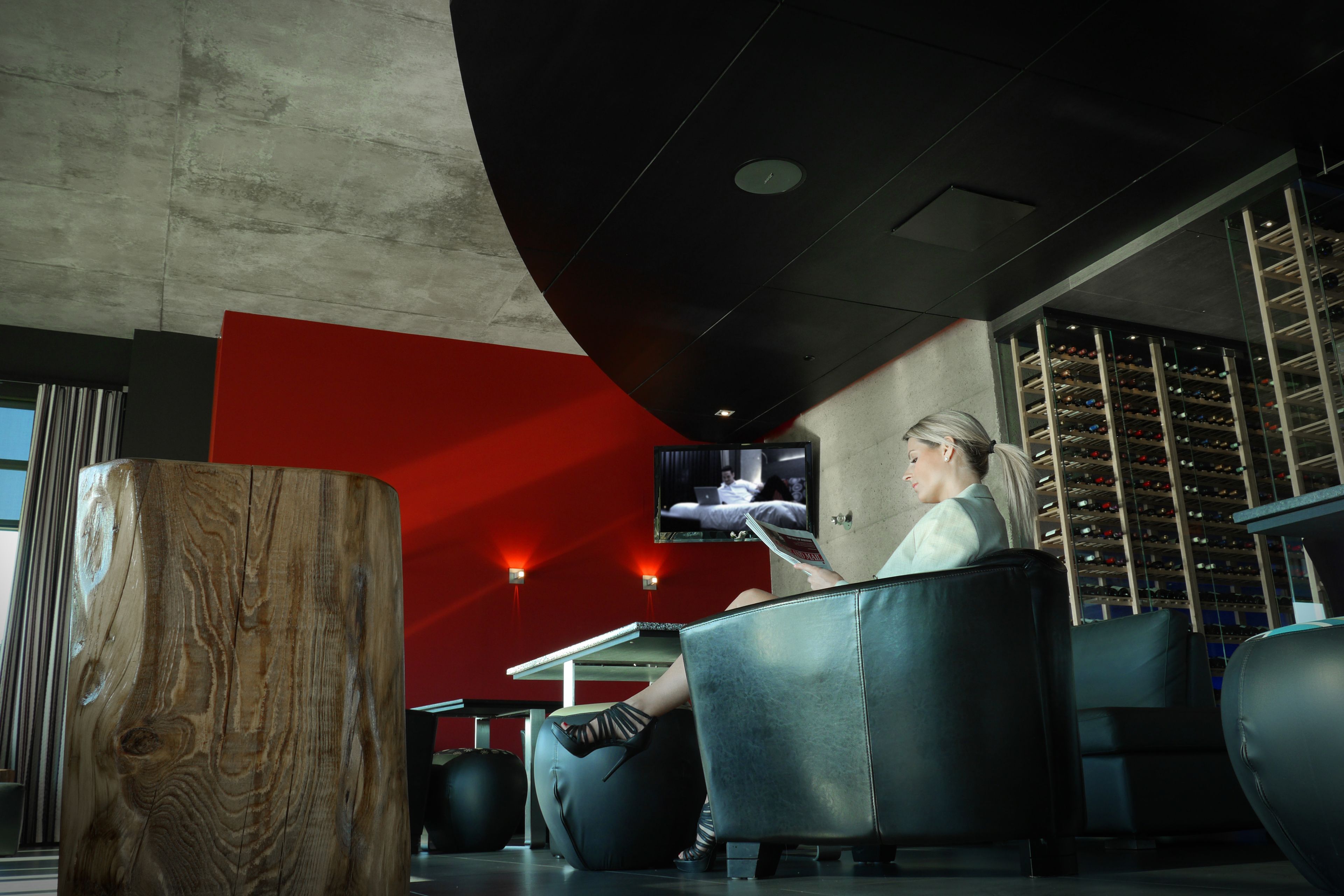 Un interior moderno con un gran poste de madera, asientos de cuero negro, una pared de acento roja y una estantería para vinos.