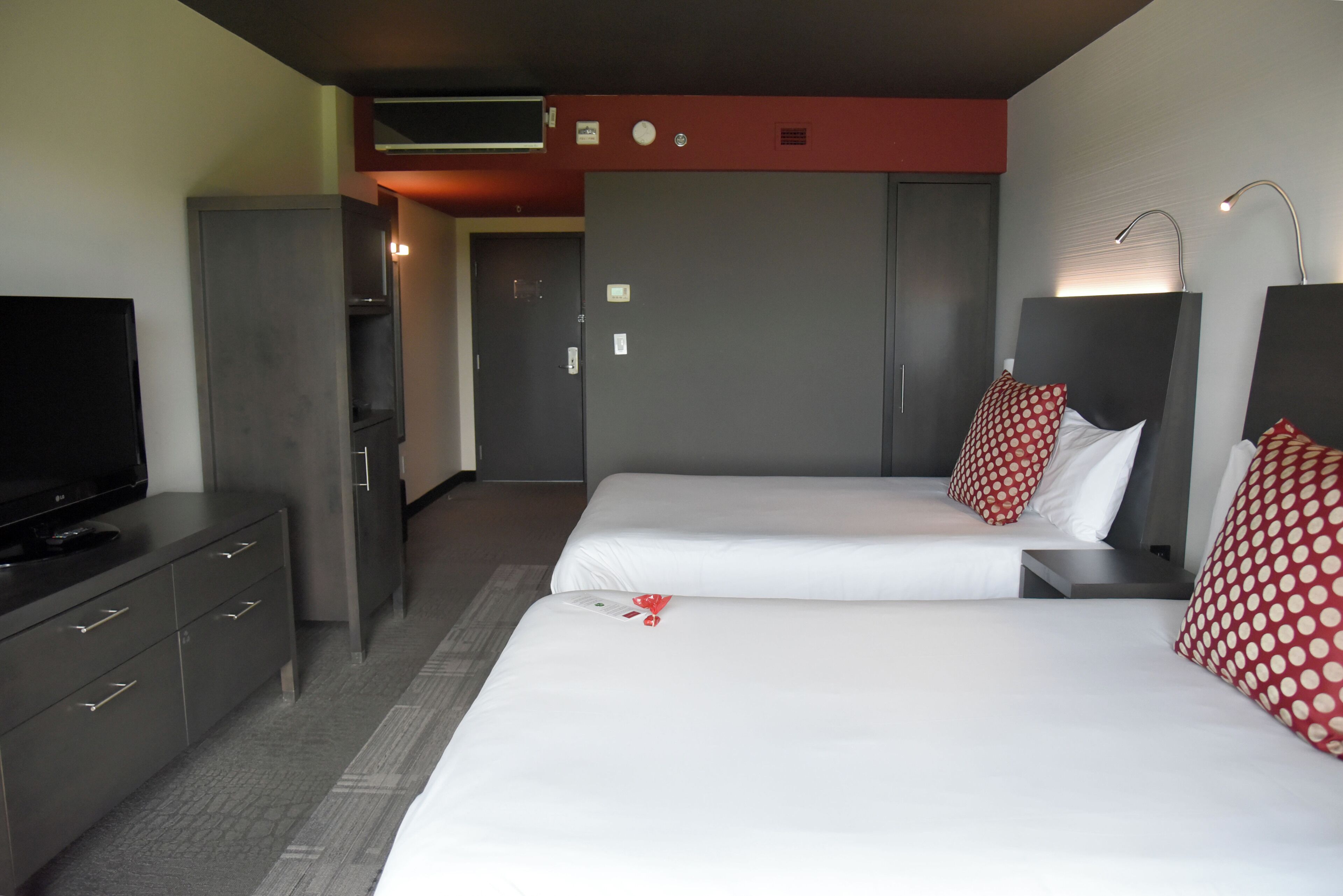 A hotel room with two beds, a TV, a wardrobe, and a desk.
