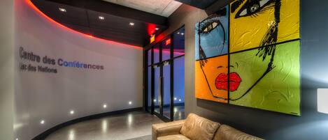 A modern lobby with a leather sofa, a large abstract painting, and a sign reading "Centre des Conferences."