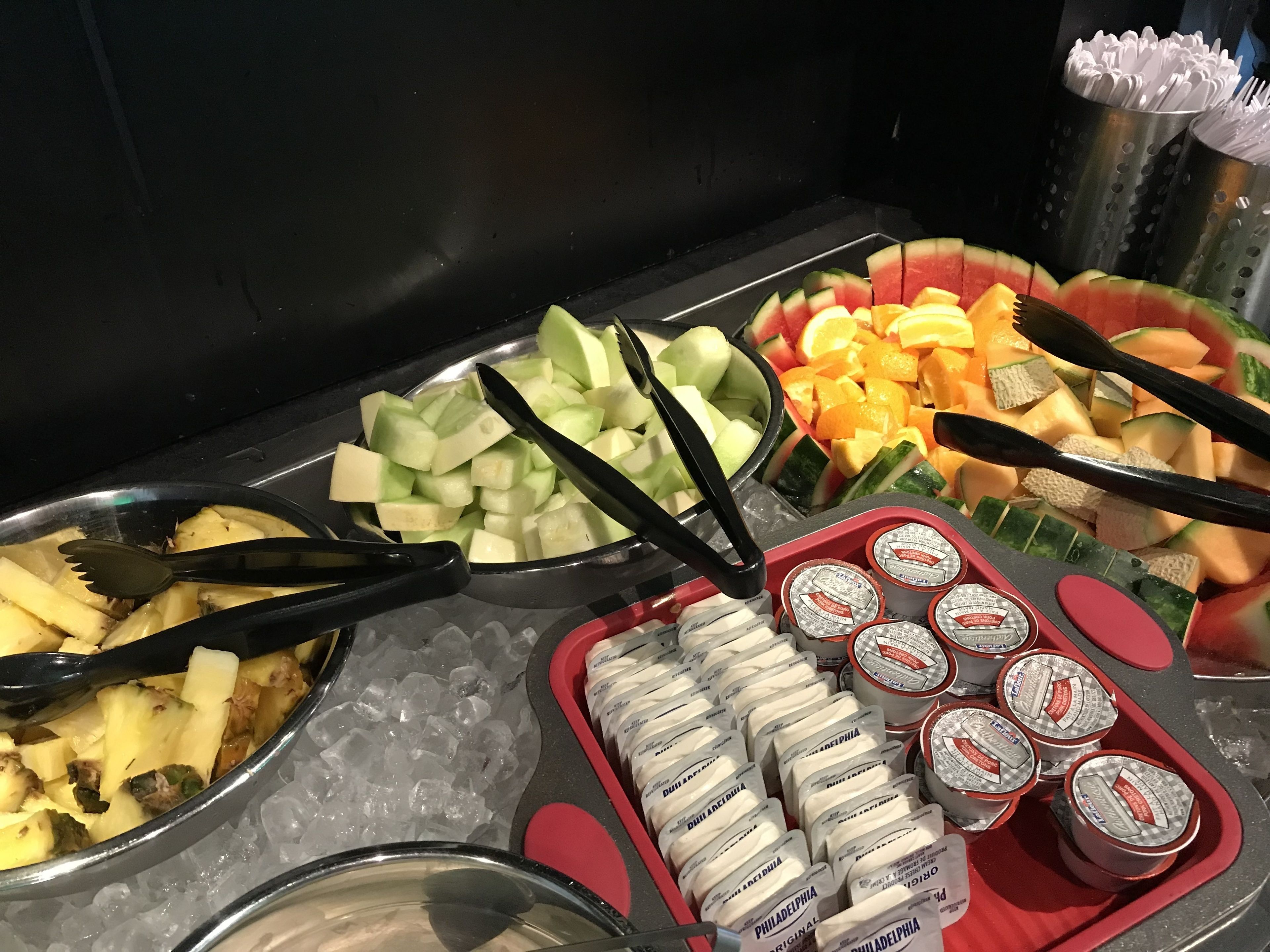 En buffet med et udvalg af frugter og is, herunder ananas, melon og appelsinskiver.
