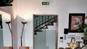 Un couloir d’hôtel avec un escalier, un comptoir d’accueil et un miroir.