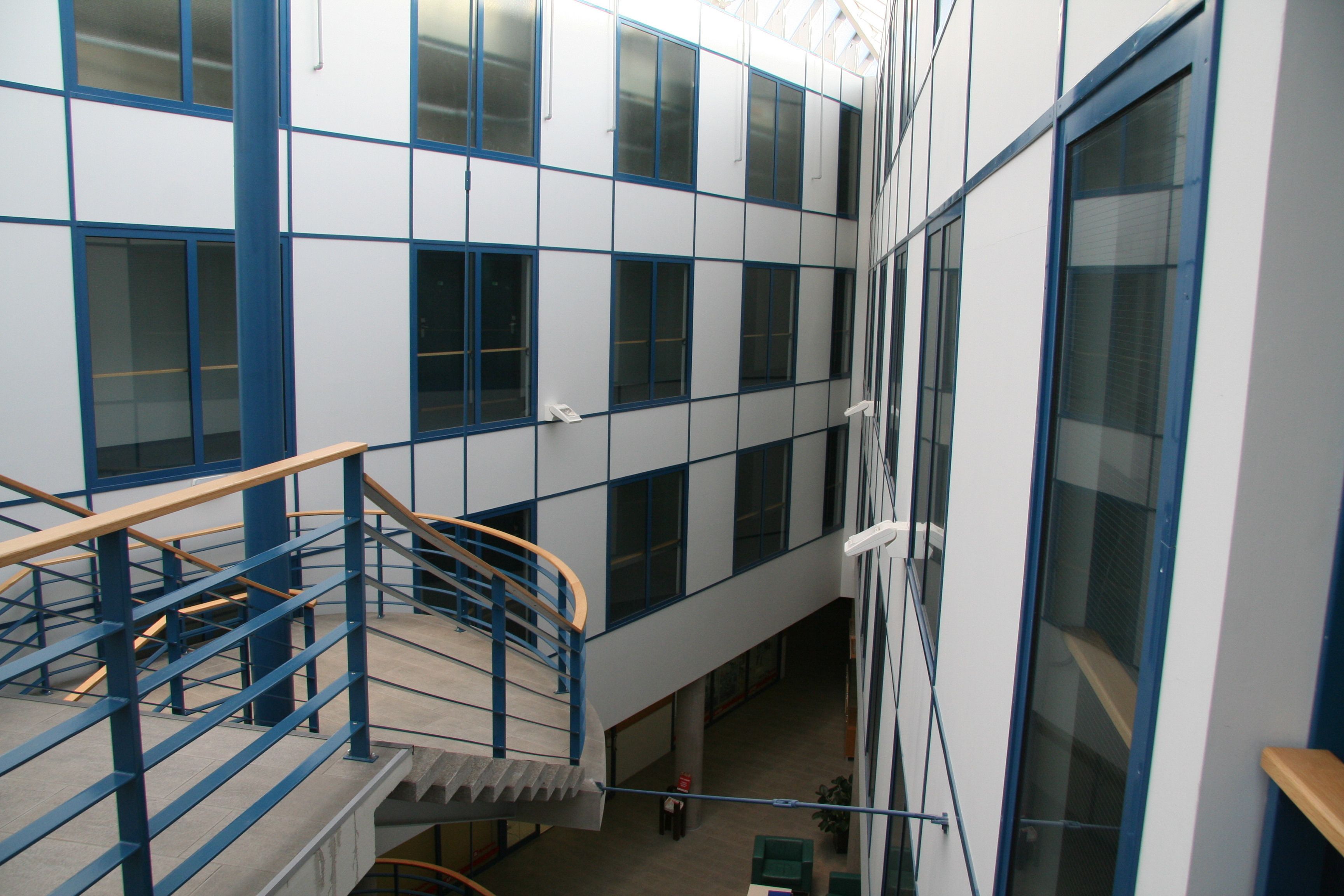 A multi-level building with a central staircase, large windows, and a blue and white color scheme.