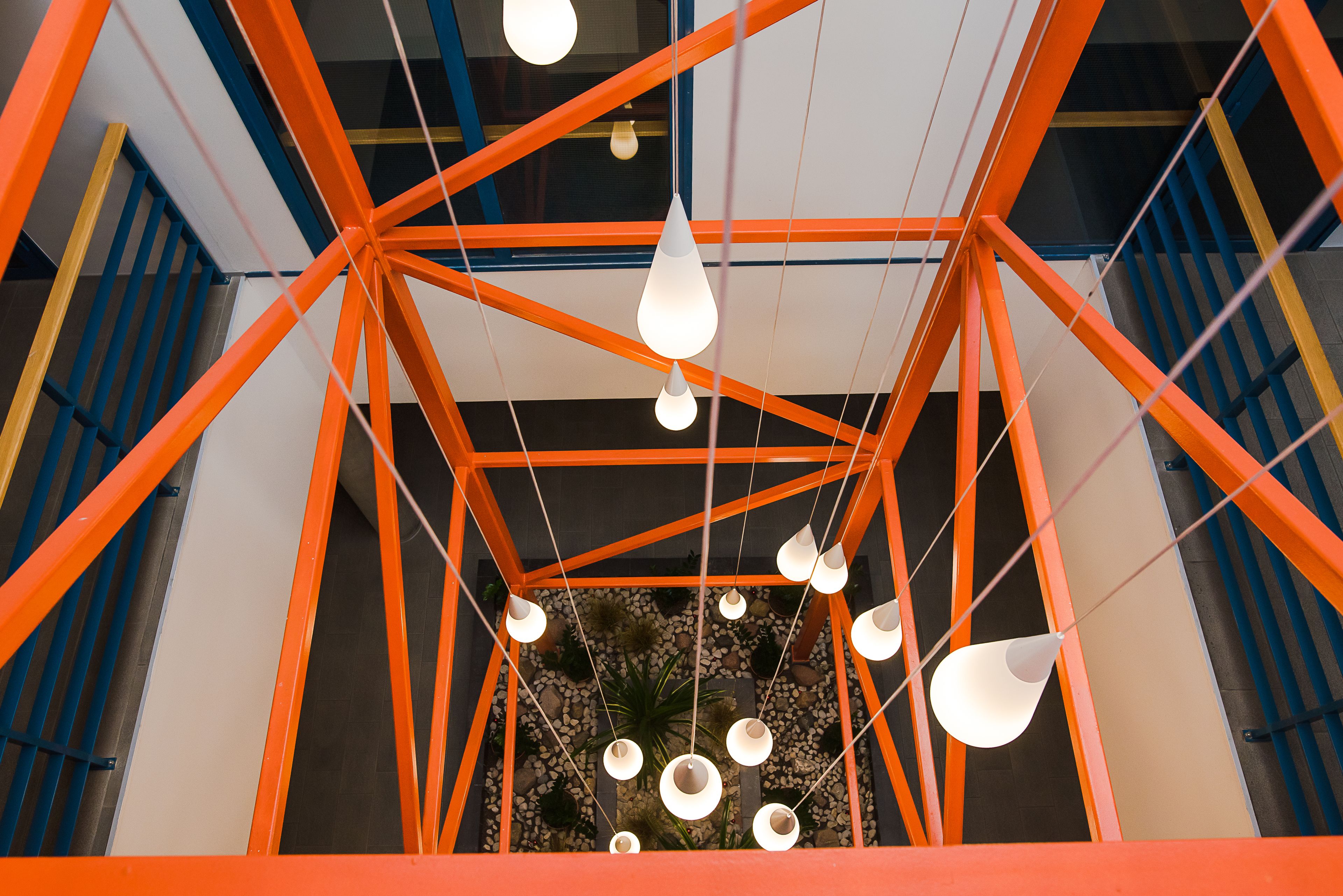 Un interior moderno con una estructura de techo geométrica y lámparas colgantes.