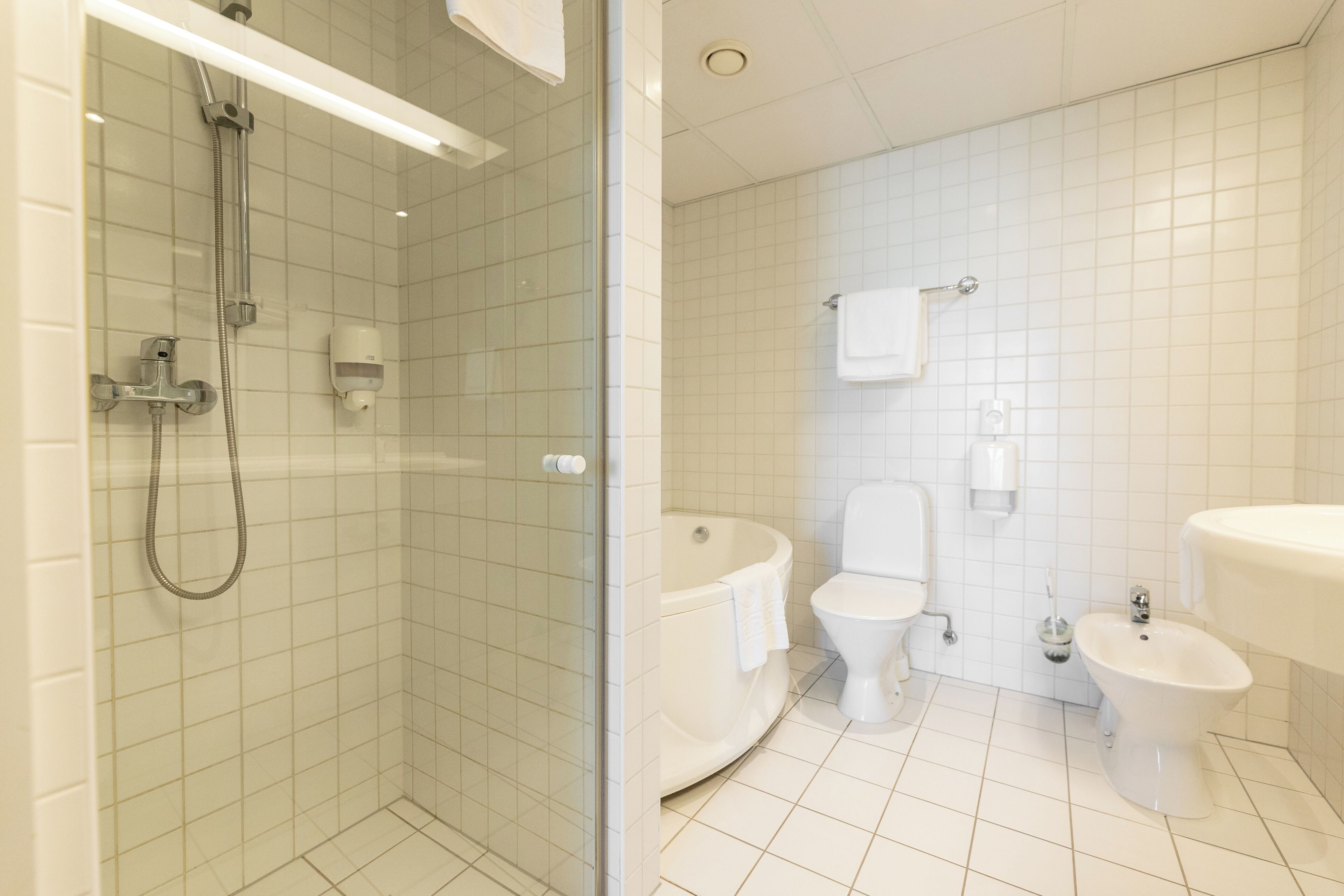 Une salle de bain comprenant une douche à parois de verre, des toilettes, un bidet et un lavabo.