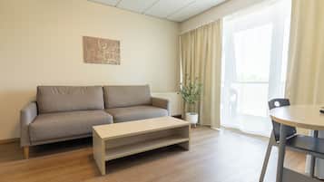 A living room with a sofa, a coffee table, a potted plant, and a dining table.