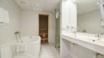 A modern bathroom with a bathtub, toilet, and a large mirror.