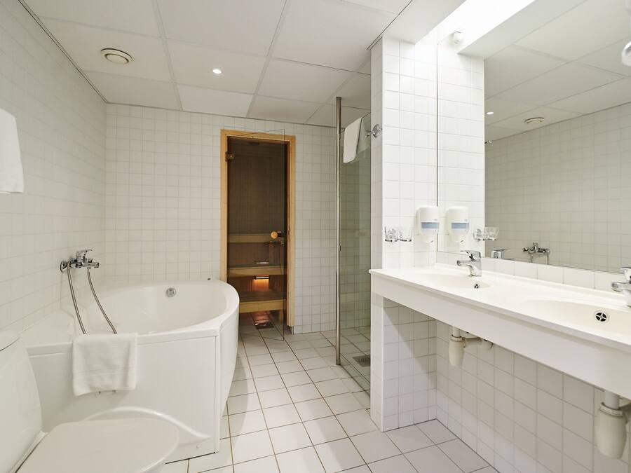 Moderni kylpyhuone, jossa on kylpyamme, wc ja suuri peili.
