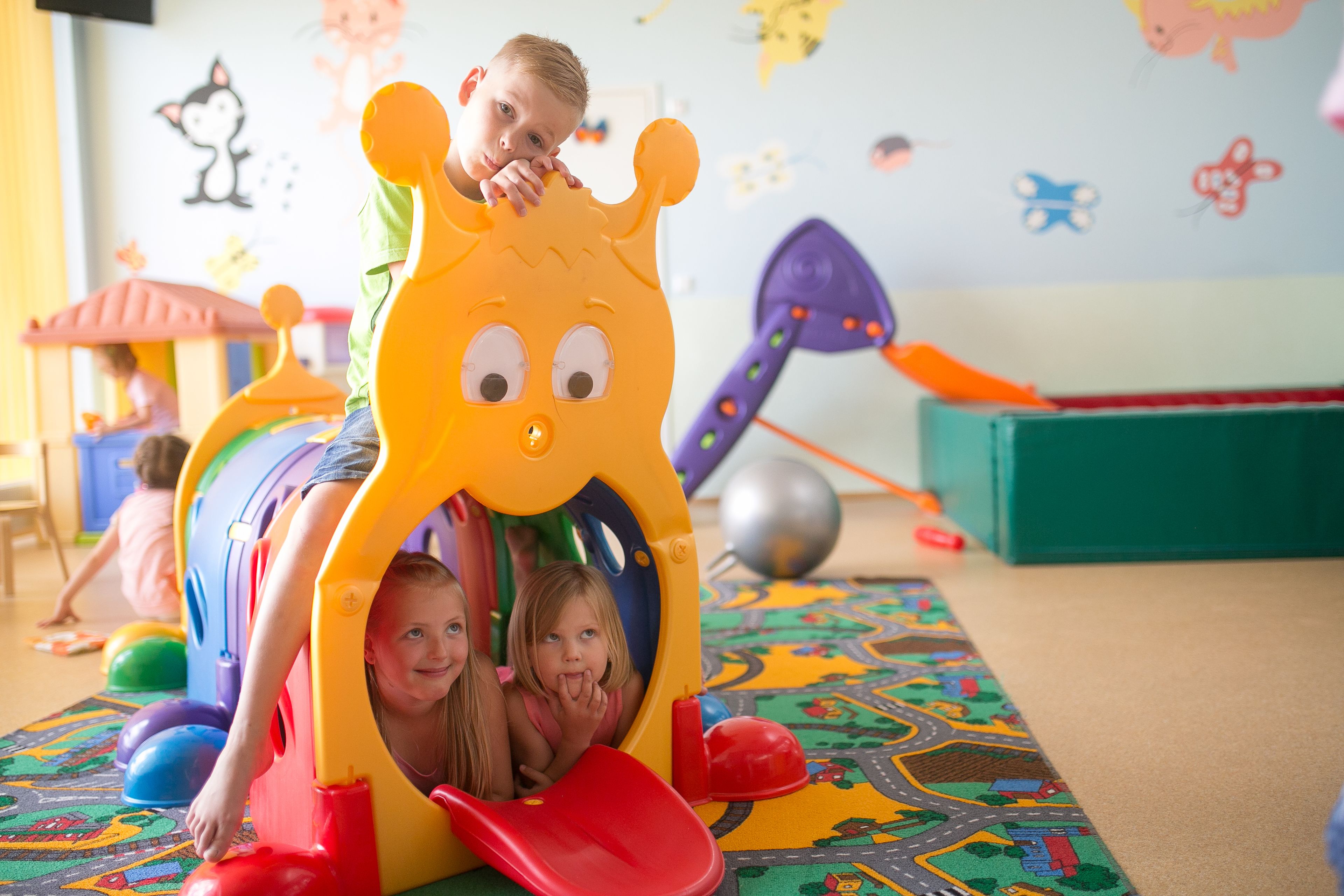 Children playing in a colorful play area with a slide and various toys.