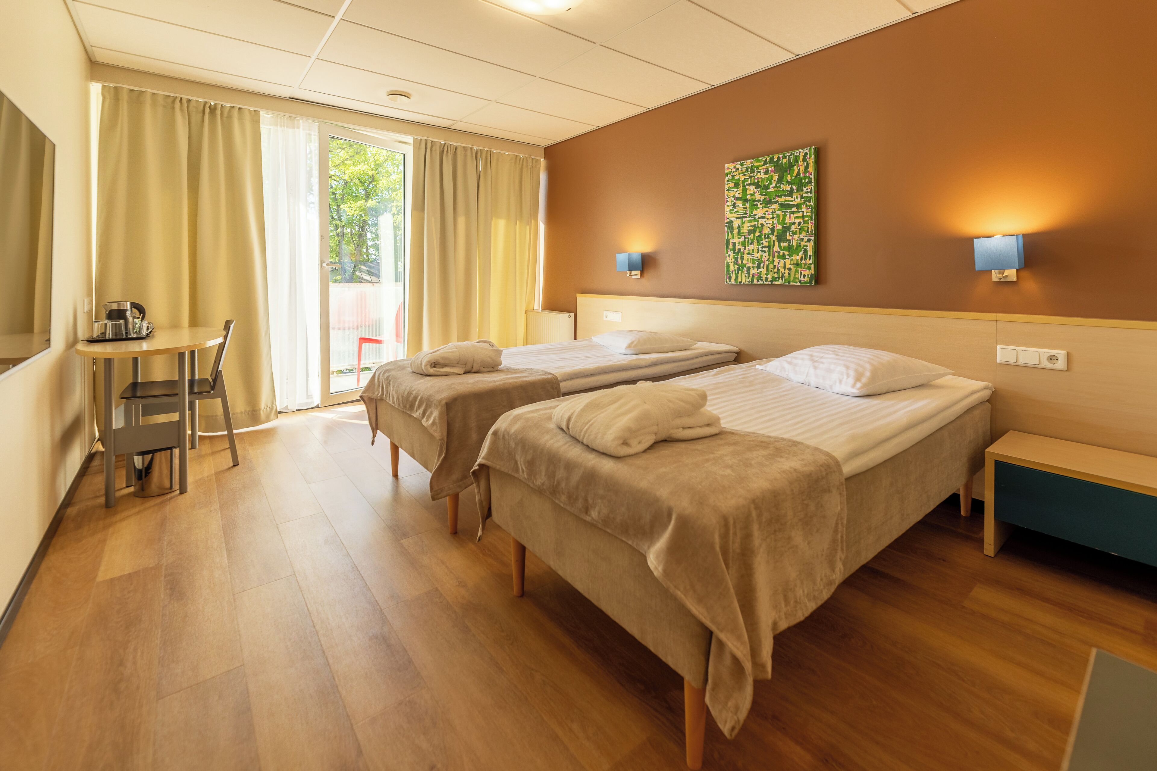 Habitación de hotel con dos camas, un escritorio y vistas al exterior.