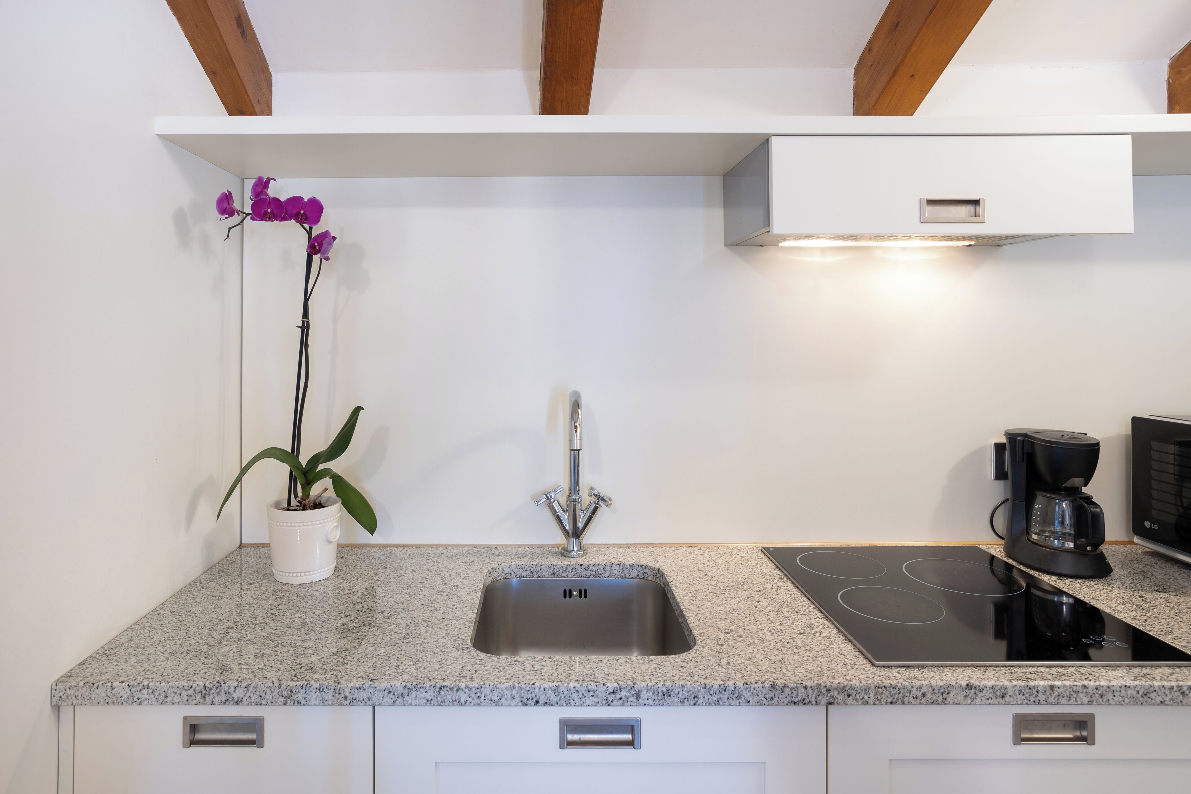A modern kitchen with a granite countertop, stainless steel sink, and built-in stove.