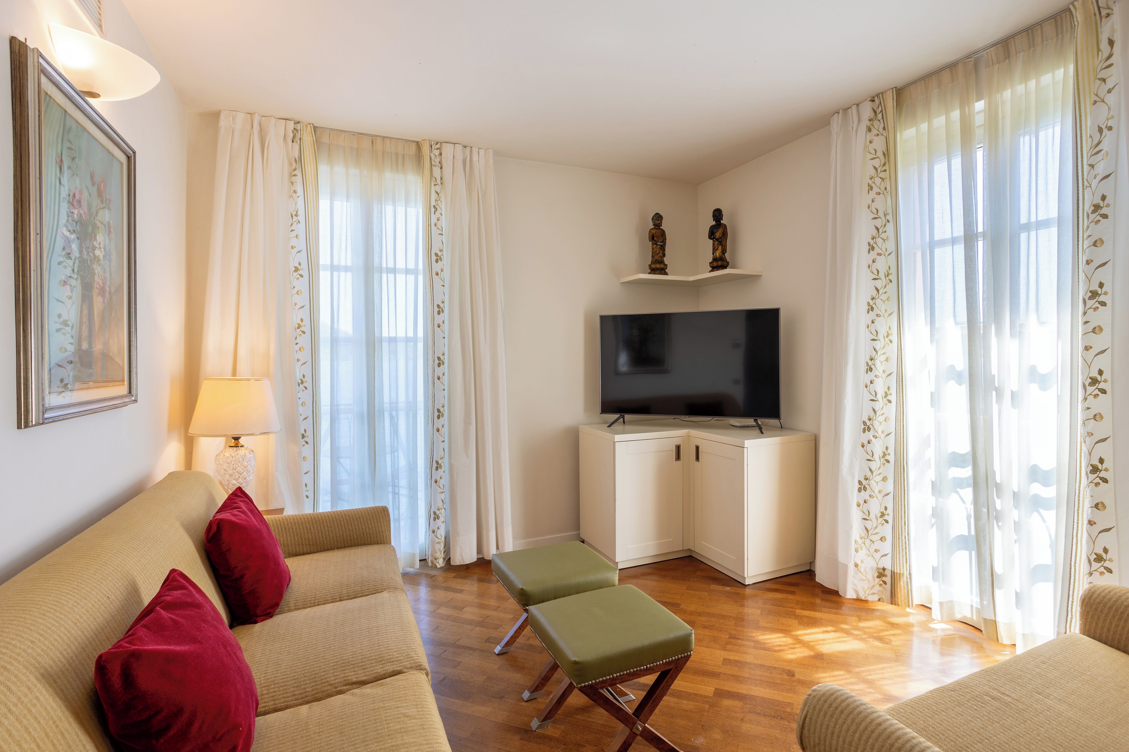 A living room with a sofa, ottoman, TV, and cabinets.