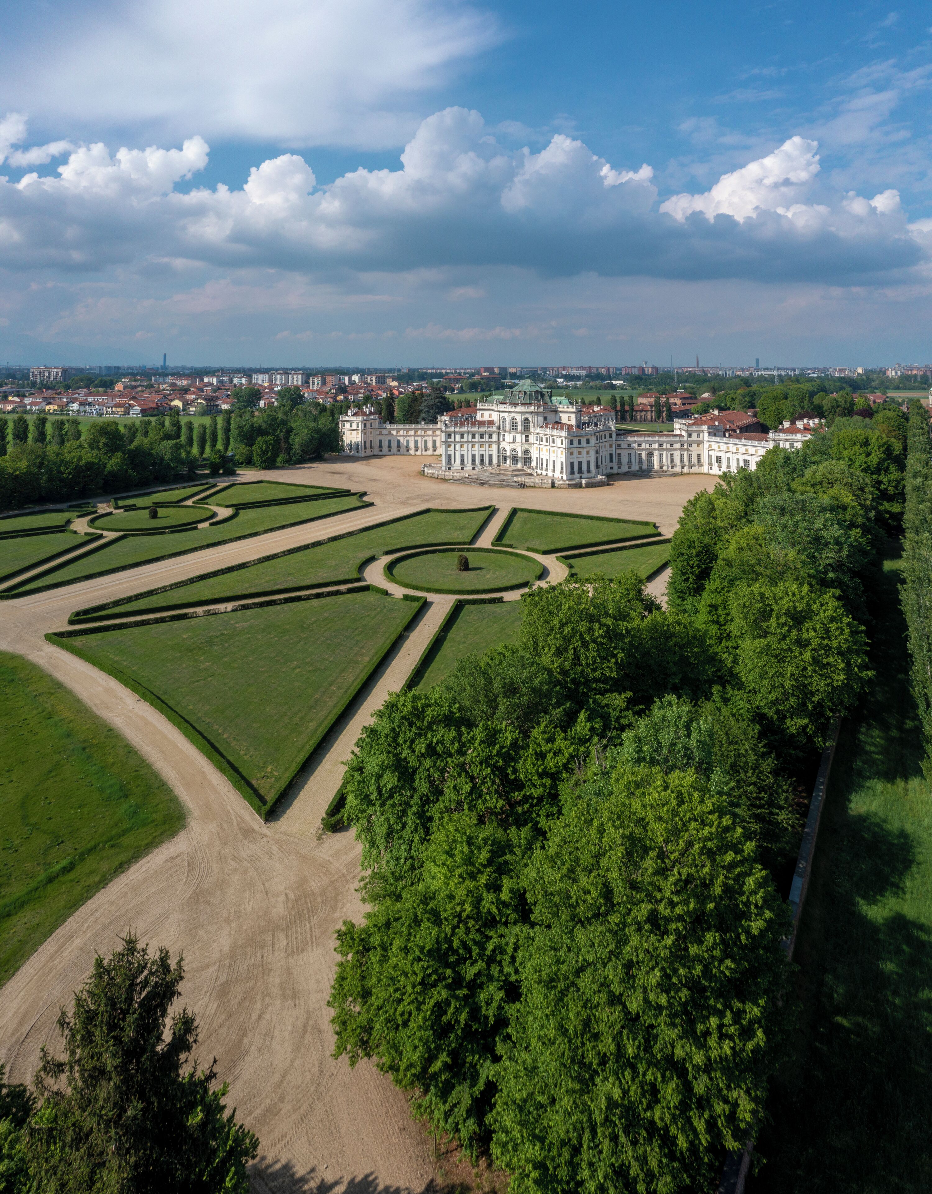 Un edificio grande e histórico con jardines formales y una distribución simétrica.