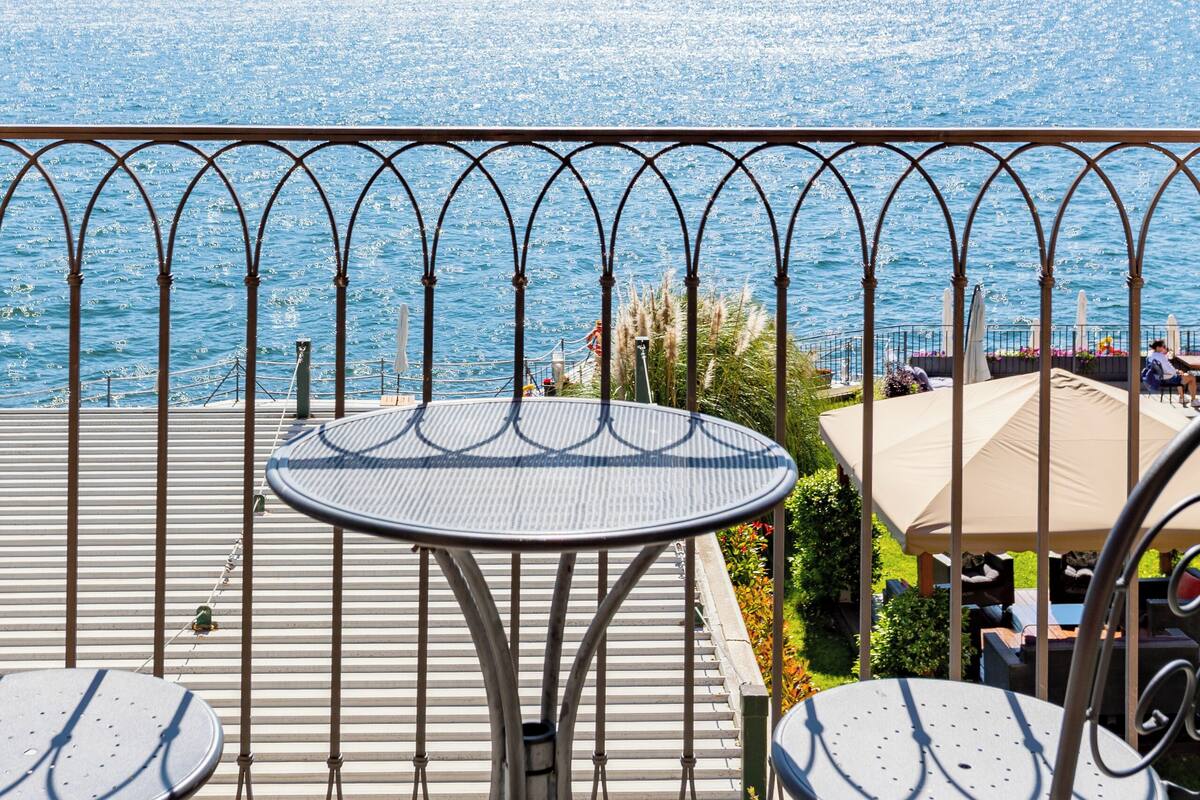 Une terrasse dotée d’une rambarde en métal, d’une table ronde et de deux chaises.