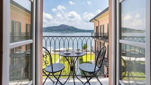 A balcony with two chairs and a small table, overlooking a lake and a mountain. - Resort Antico Verbano (Meina)