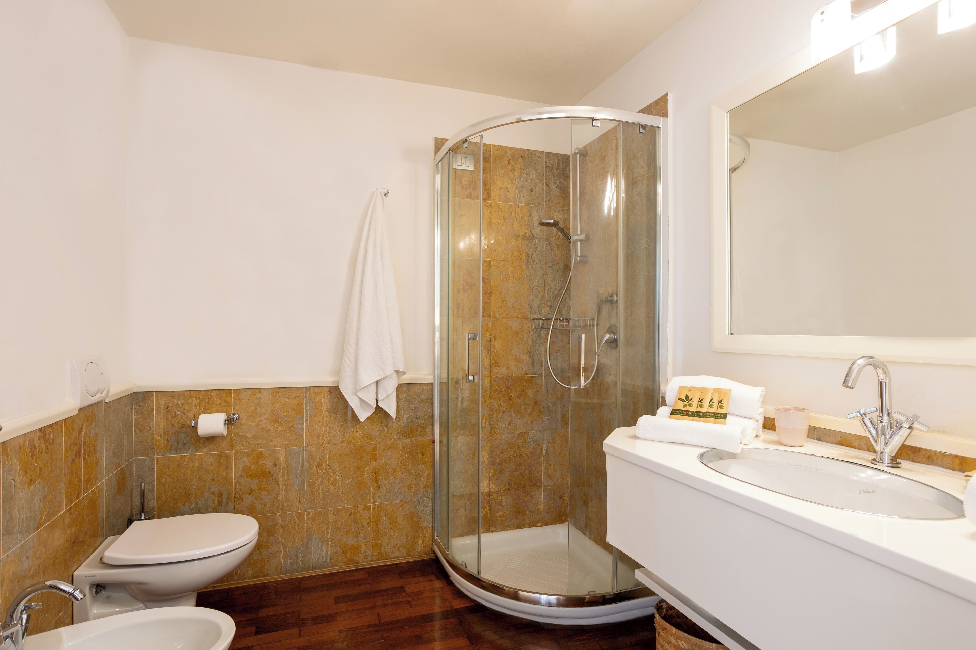 Une salle de bain avec une douche à parois de verre, des toilettes et un lavabo avec un miroir au-dessus.