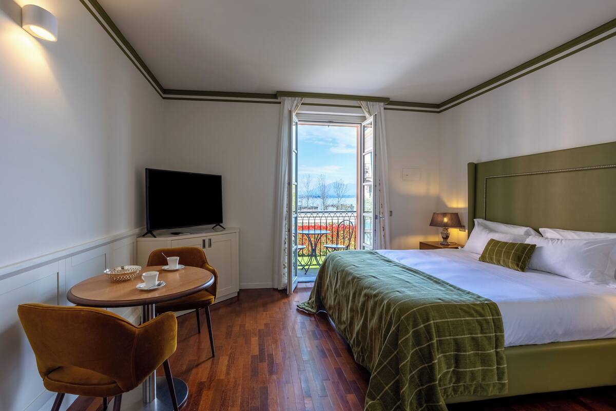 Une chambre d’hôtel comprenant un lit, une télévision, une table à manger avec des chaises et un balcon avec vue.
