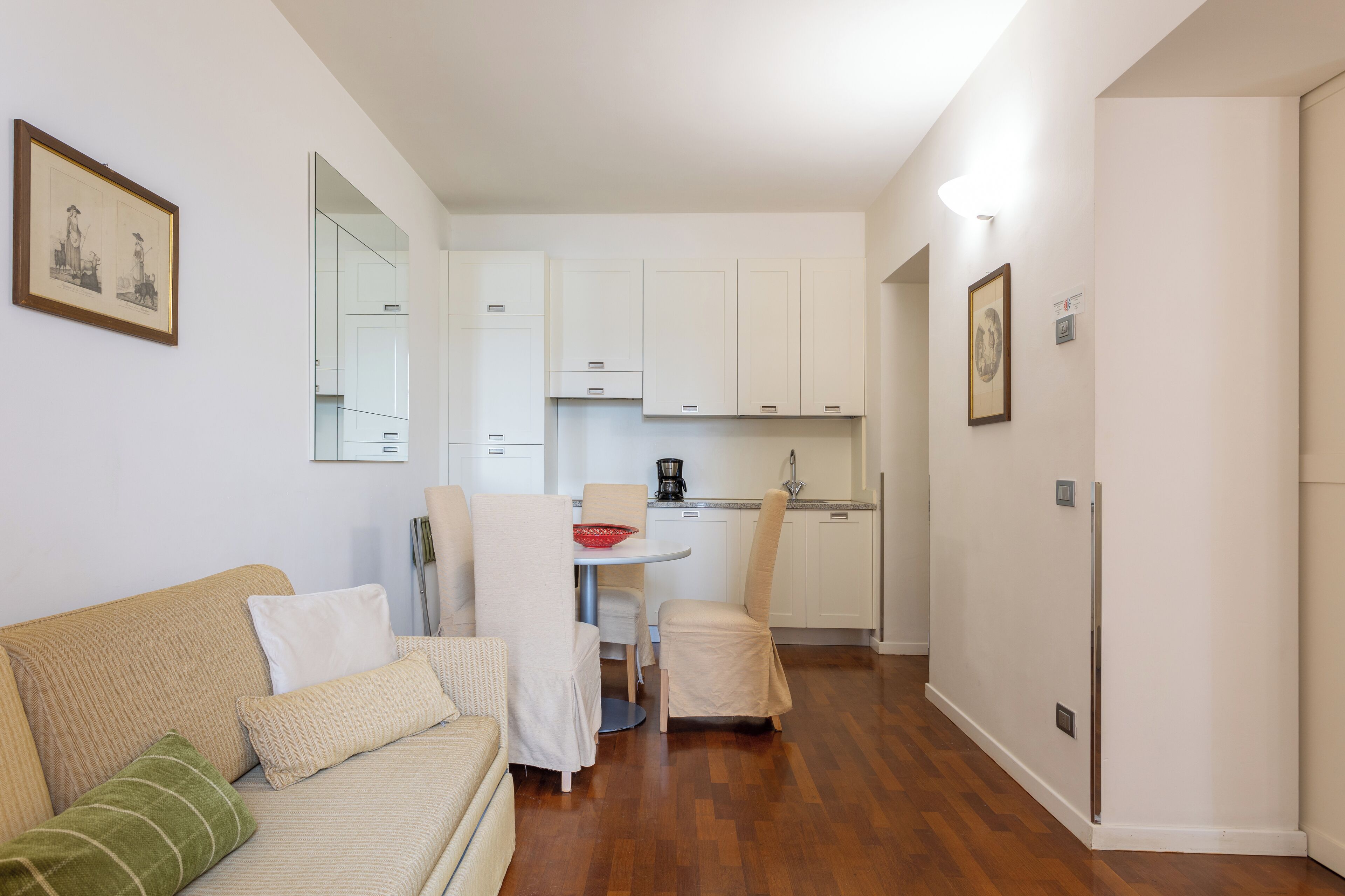 Un espacio habitable compacto con sofá, mesa de comedor y zona de cocina.
