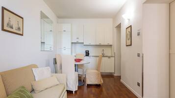 Un espacio habitable compacto con sofá, mesa de comedor y zona de cocina.