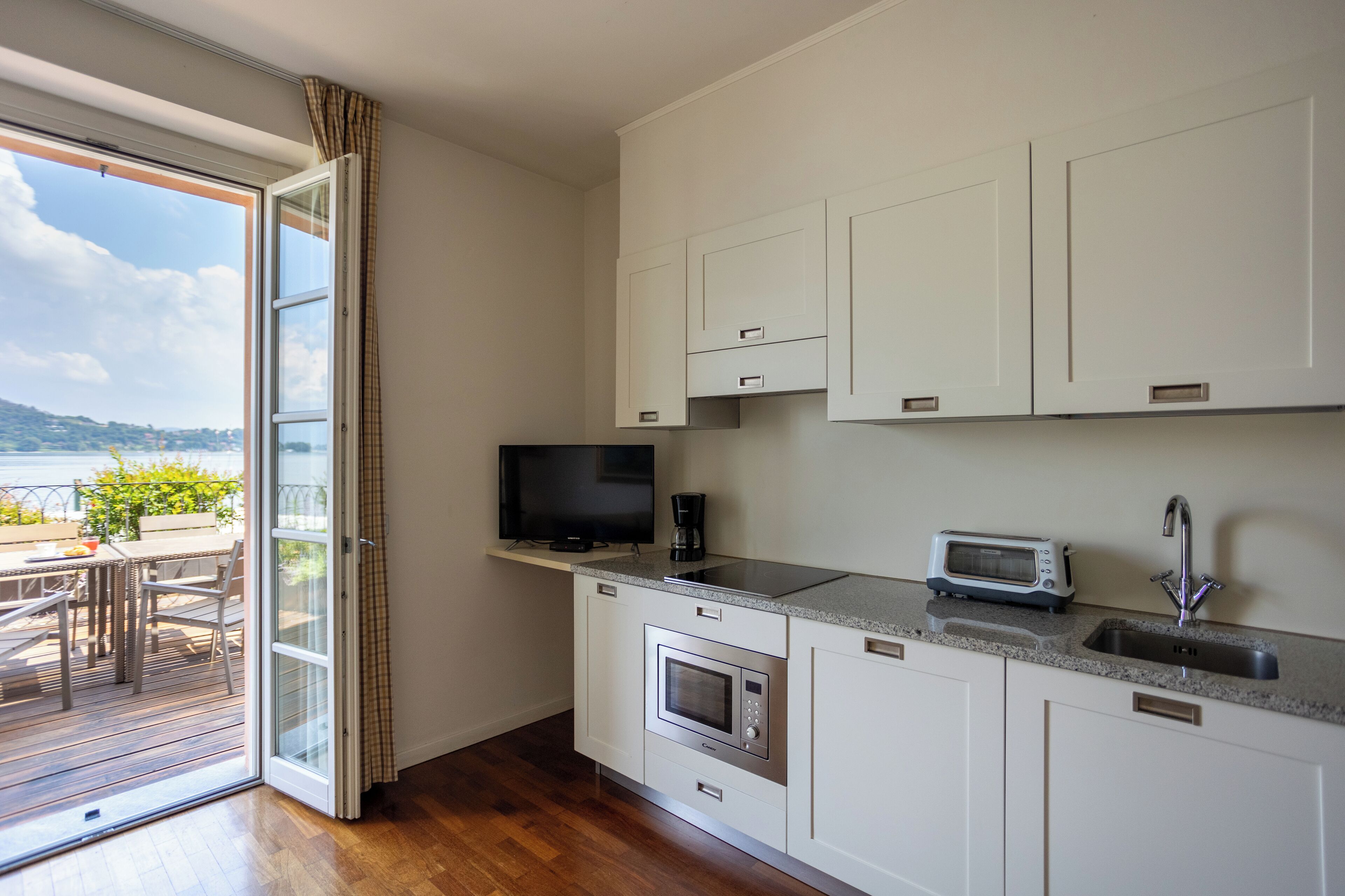A modern kitchen with white cabinets, a built-in microwave, a toaster, and a sink.