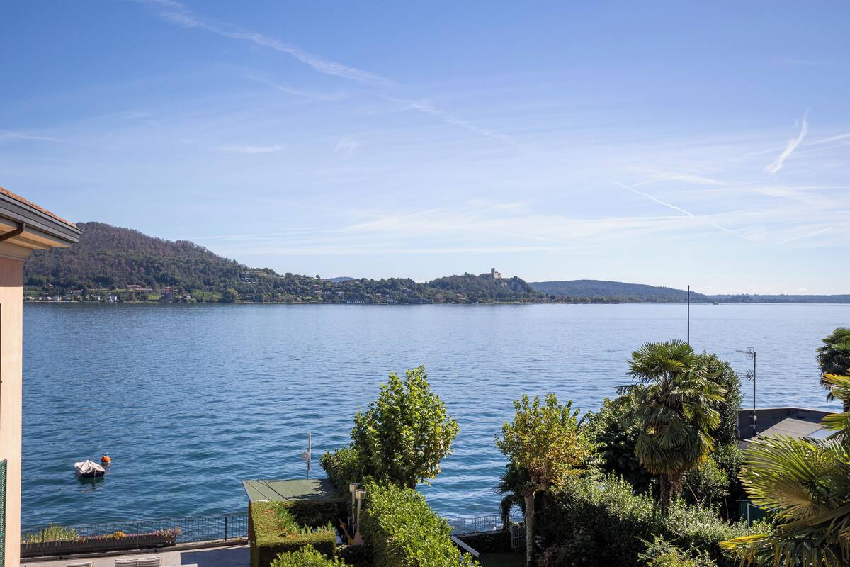 Un lac avec vue sur une colline lointaine et un bâtiment doté d’un balcon surplombant l’eau.