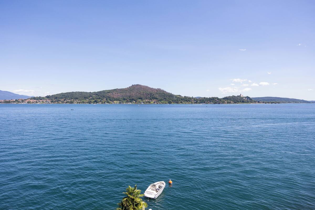 Un lac avec un bateau au premier plan et, au loin, une colline parsemée de bâtiments.