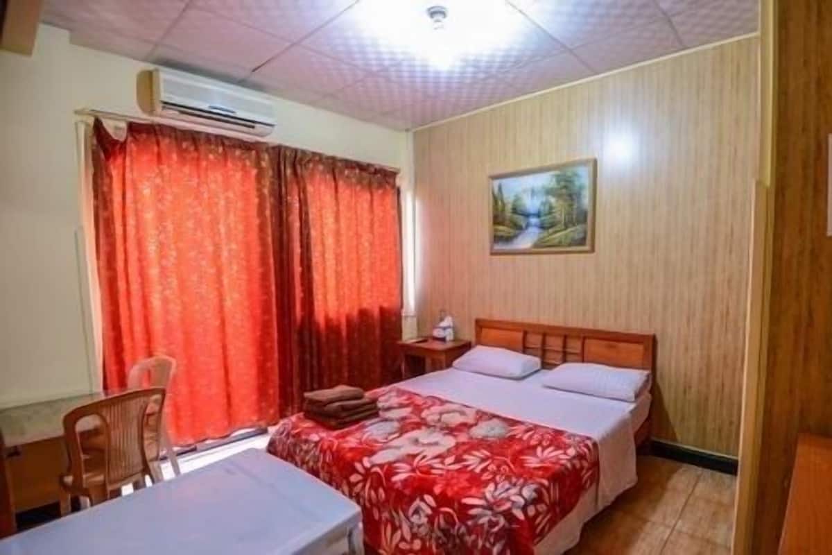 Une chambre d’hôtel équipée d’un lit, d’un bureau, d’une chaise, d’un tableau au mur et d’un appareil de climatisation.